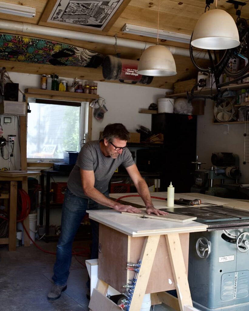 Man wearing dark glasses and a grey t-shirt working in his workshop