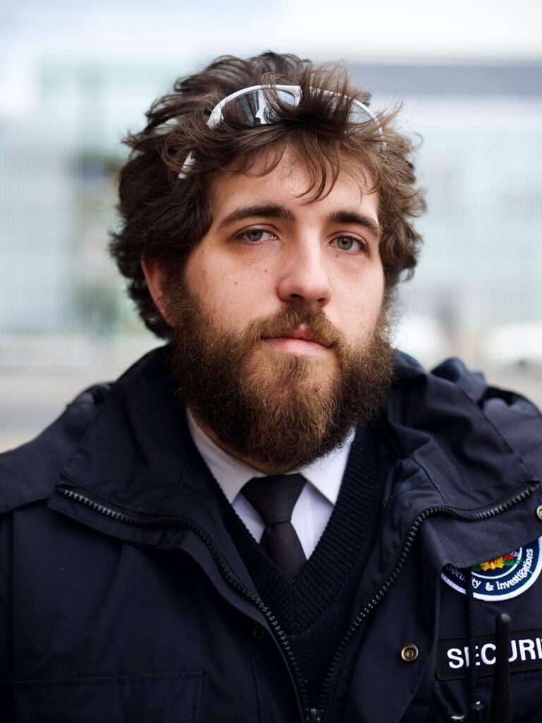 Young bearded security guard with white glasses on his head. Portrait by Geoffrey Butler