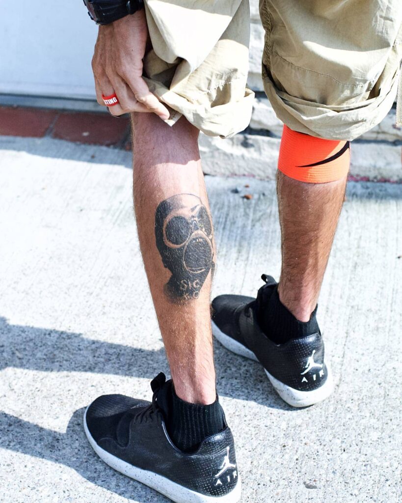 Man in Air Jordans showing off his leg tattoo of Sid Wilson from Slipknot.